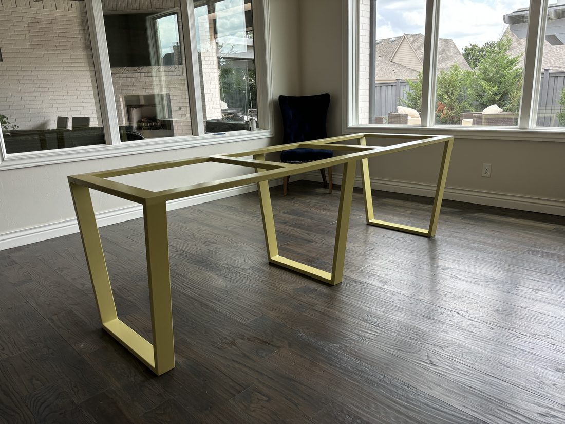 Brass-tone rectangular metal table bases on a wood floor.